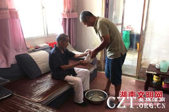 周仁南（右一）给已故妻子前夫的父亲擦手。图片来源：湖南文明网