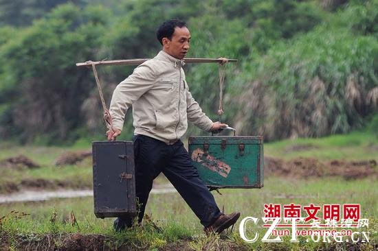 马恭志挑着电影放映机下乡。图片来源：湖南文明网