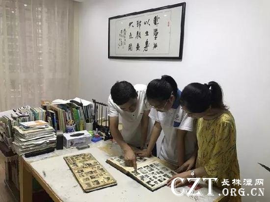 方汞和妻子何思佳与女儿一起翻阅老照片。墙上悬挂家训“非学无以立身,非教无以立国”。(袁汝婷 摄)
