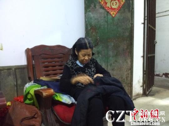 李新彩老人给张满英缝补衣服。 谢丽萍 摄